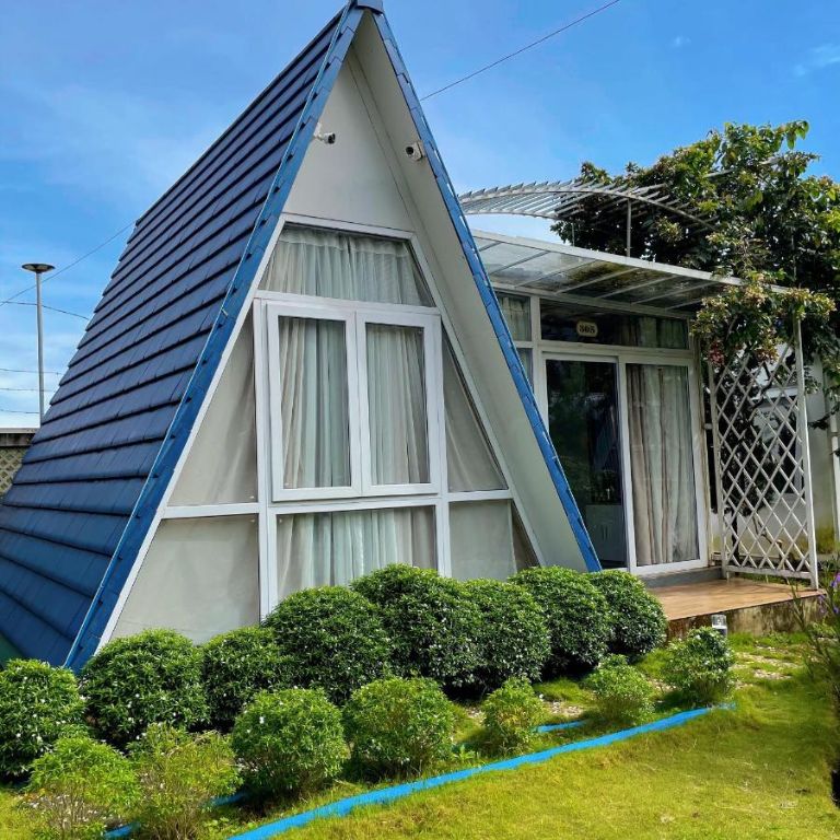 Bungalow này có hình dáng khối tam giác độc đáo với mái ngói màu xanh dương nổi bật, tạo nên không gian nghỉ ngơi độc đáo tại Bảo Lộc.