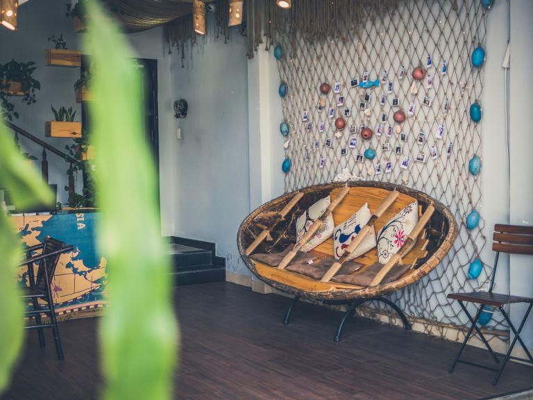 Homestay có sàn nhà bằng gỗ và bức màn xanh rêu cá tính, với ghế bằng nan độc đáo và bức tường kỉ niệm của những vị khách đã từng lưu trú tại đây (nguồn: facebook.com)