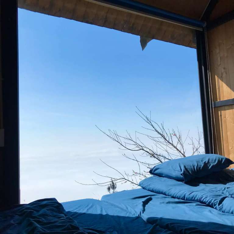 Phòng ngủ tại homestay có hệ thống cửa kính ngắm nhìn ra toàn cảnh núi rừng Tây Bắc hùng vĩ 