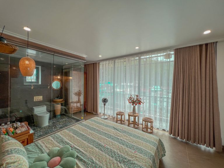 Phòng ngủ tại homestay vịnh Lan Hạ này có hệ thống cửa kính lớn và rèm che có thể điều chỉnh ánh sáng bên ngoài tràn vào phòng