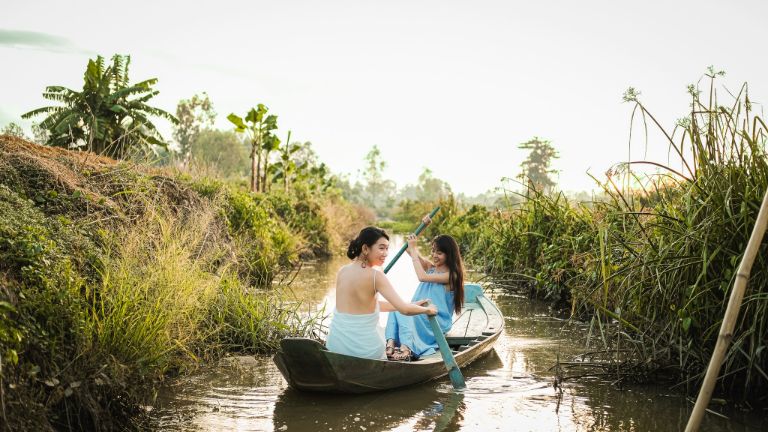 Trải nghiệm tự chèo thuyền gỗ trên kênh nước nhỏ của du khách lưu trú tại homestay Đồng Tháp.