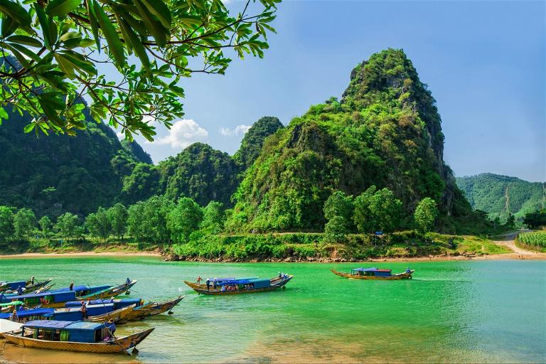 Dòng sông xanh ngắt, trong veo, hai bên là núi đá vôi sừng sững.