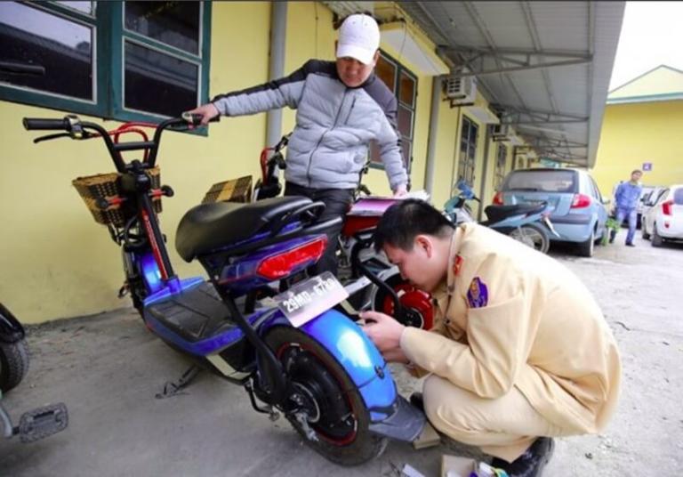 Cán bộ công an hướng dẫn chủ xe chà số khung và số máy để đối chiếu.