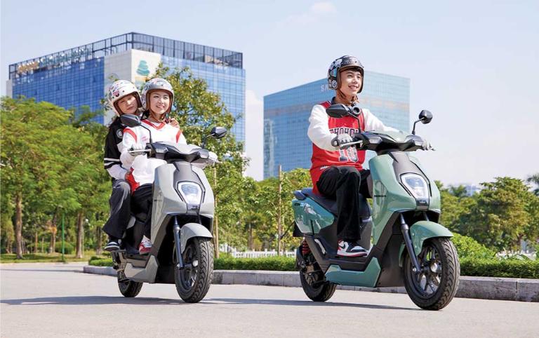 Người dùng dắt xe máy điện nhẹ nhàng trong ngõ nhỏ, so với xe xăng nặng và đầm chắc hơn.