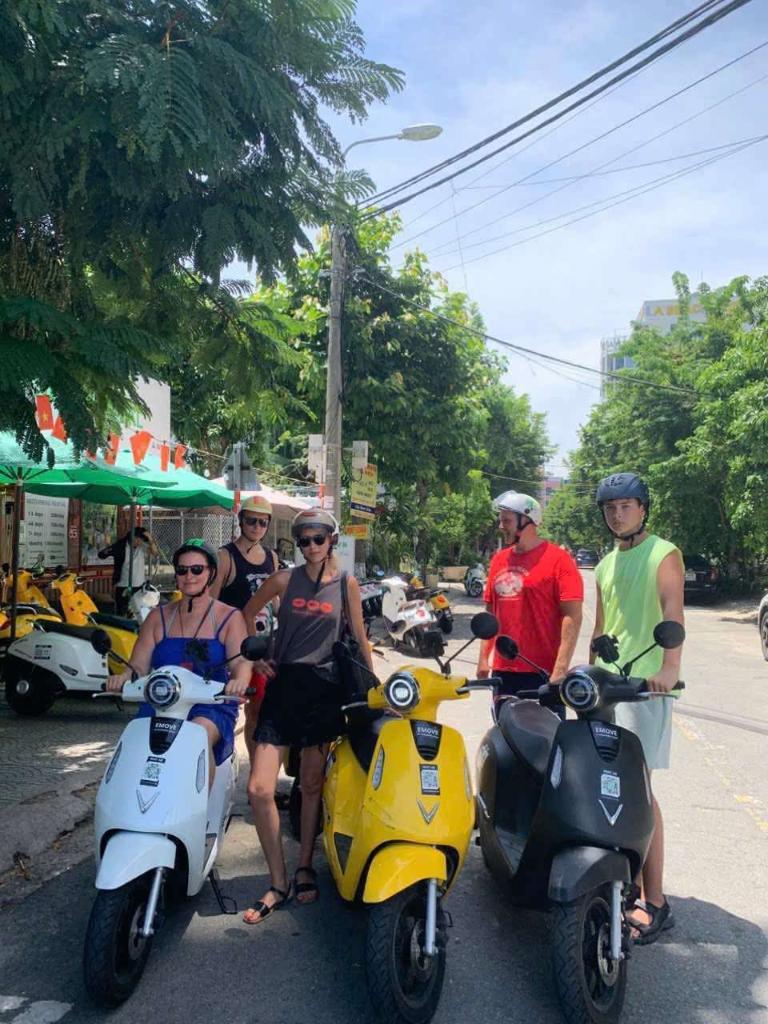 Khách du lịch nước ngoài trải nghiệm tour bằng xe máy điện dọc bãi biển Đà Nẵng.